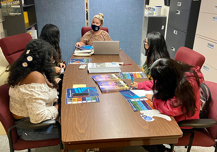 Counselor shows college brochures to four students