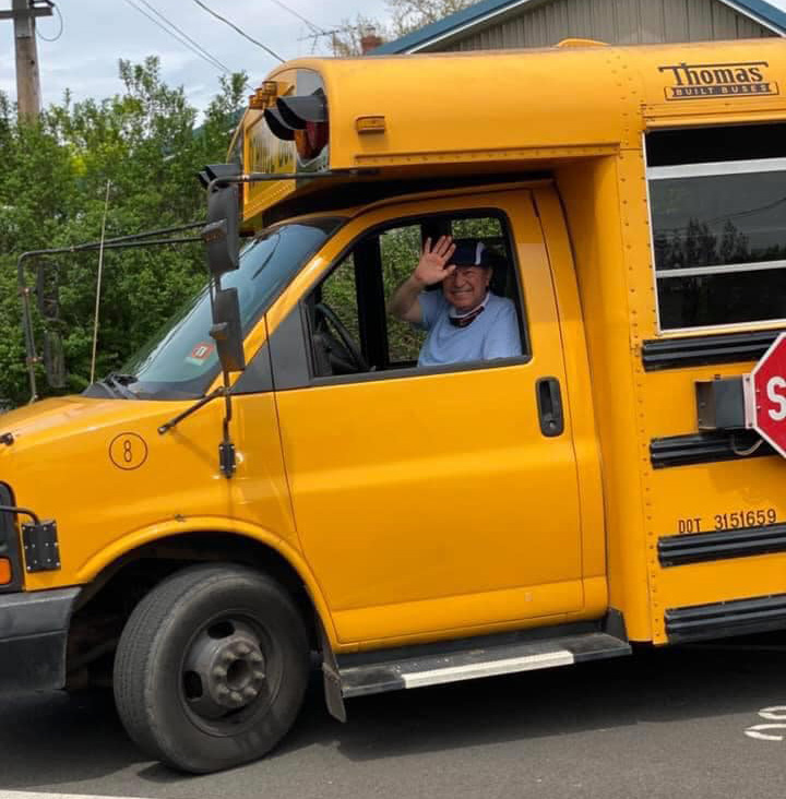 Driver waves out the window of a school bus