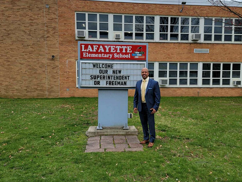 Superintendent Alvin Freeman stands in front of a Lafayette Elementary School sign that welcomes him to the district