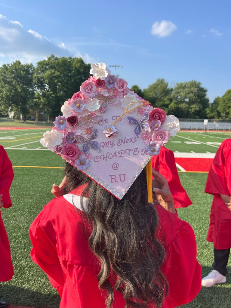 A graduation cap adorned with flowers that reads, "On to the next chapter."